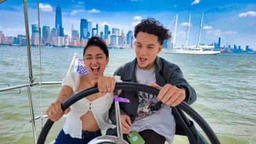 Romantic couple at the helm of a sailboat with Manhattan skyline